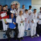 Na slici je grupa ljudi koji su osvojili nagrade na natjecanju u parataekwondou. svi drže diplome u rukama. Pozadina prikazuje plakat sa natpisom “PARA TAEKWONDO” Na podiju su označena mjesta 1, 2 i 3, što ukazuje na pobjedničke pozicije.