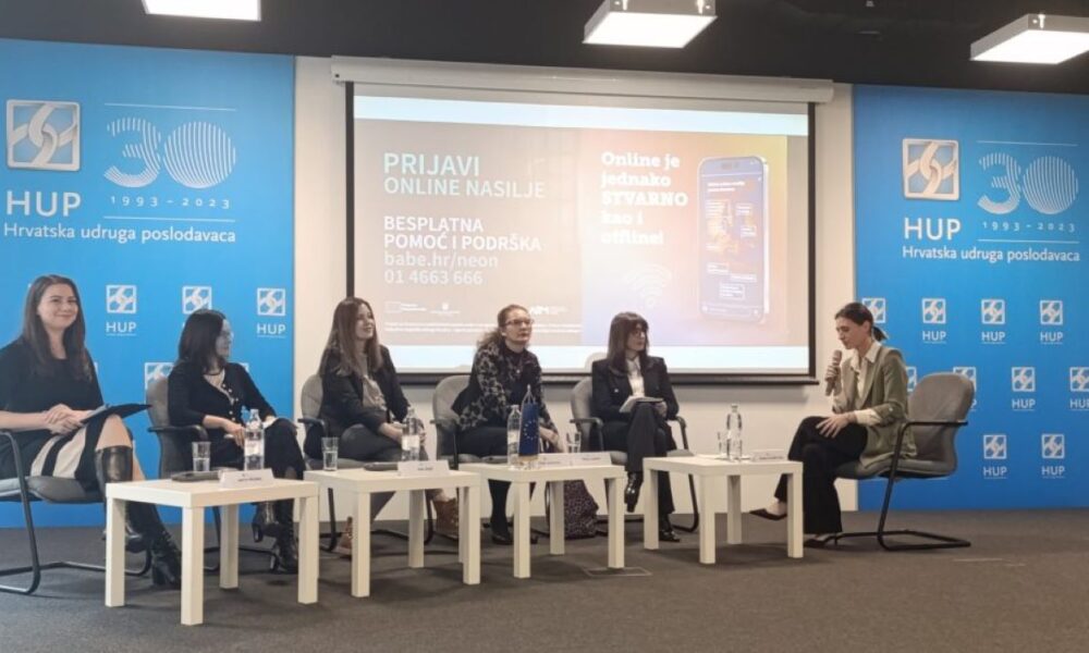 Na fotografiji je panel diskusija s pet osoba koje sjede za stolom. Pozadina prikazuje plavi banner s logotipom i tekstom “HUP Hrvatska udruga poslodavaca”. Na ekranu iza sudionika prikazana je prezentacija koja promovira aplikaciju za prijavu online nasilja.