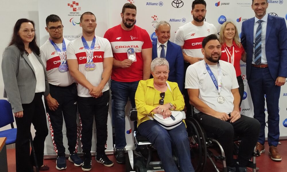 Fotografija prikazuje grupu ljudi, neki stoje, a neki su u kolicima. Radi se o press konferenciji za para sportaše.