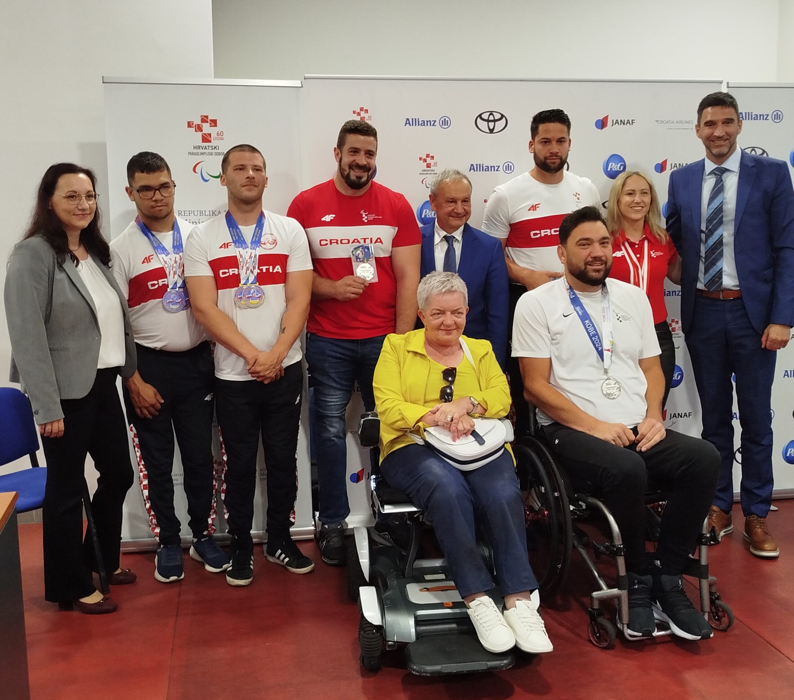 Fotografija prikazuje grupu ljudi, neki stoje, a neki su u kolicima. Radi se o press konferenciji za para sportaše.