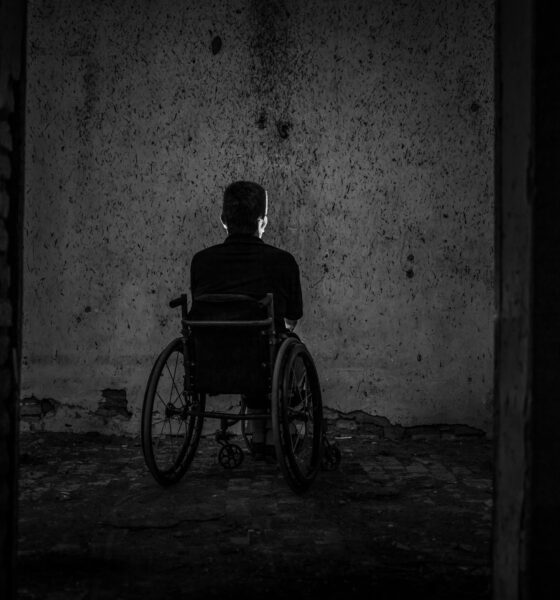 Fotografija prikazuje osobu u invalidskim kolicima koja sjedi u mraku ispred zida. To može značiti da je osoba napuštena ili da se osjeća tužno.