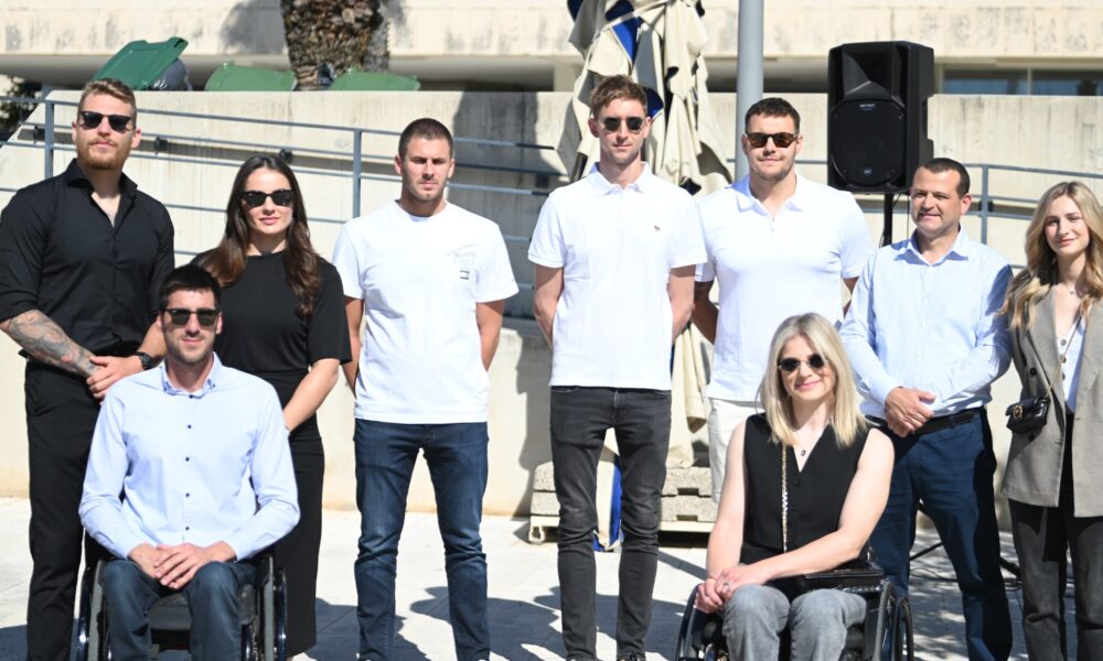 Na fotografiji je više ljudi neki stoje, a neki su u invalidskim kolicima.