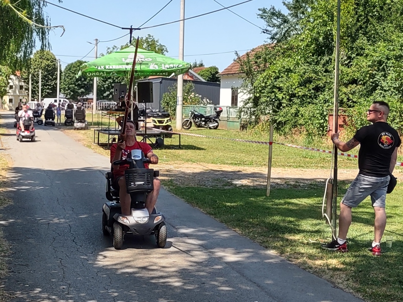 Na fotografiji je čovjek na elektromotornim kolicima koji štapom pokušava pogoditi u sredinu.