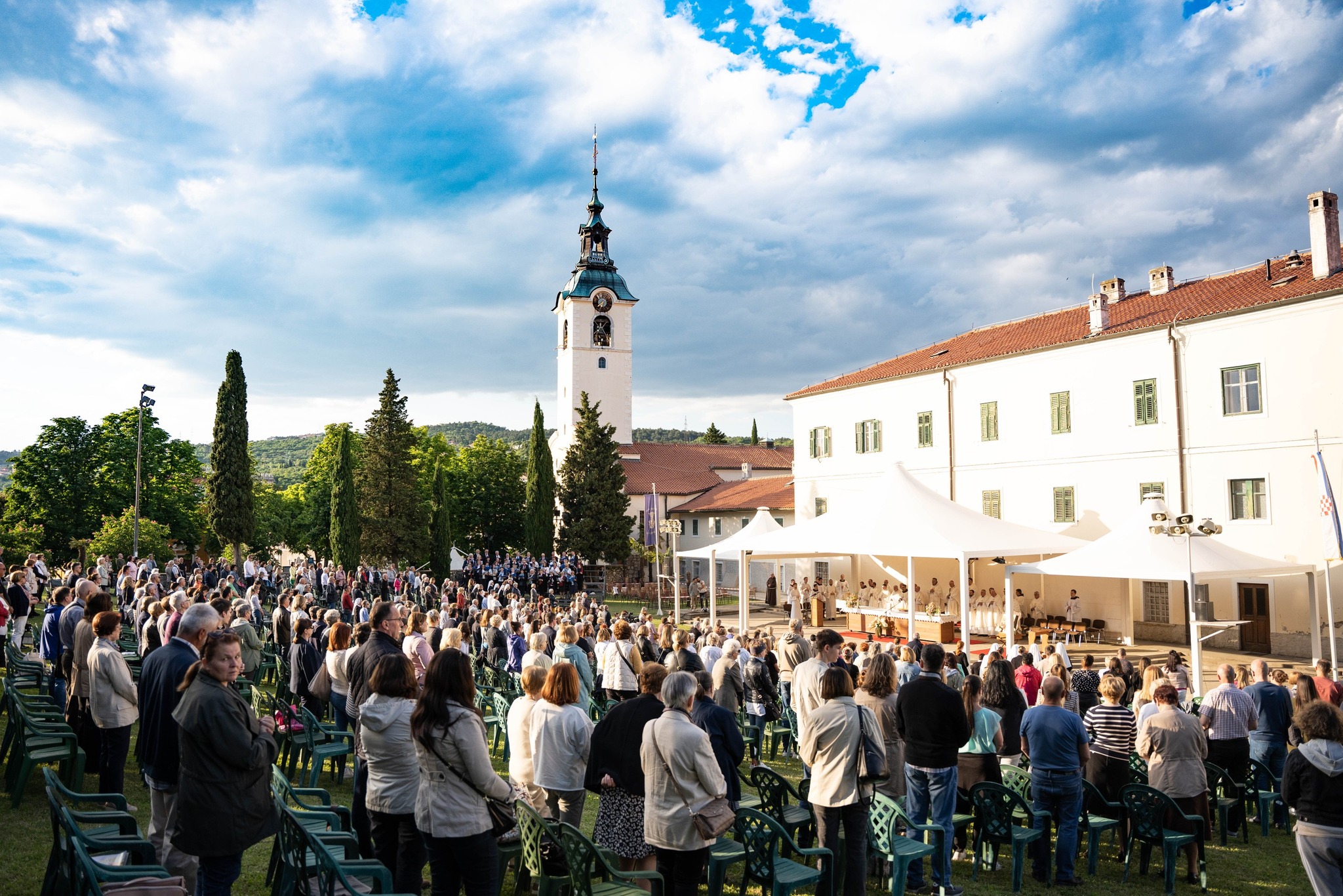 Fotografija prikazuje vjernike kako se mole ispred crkve.