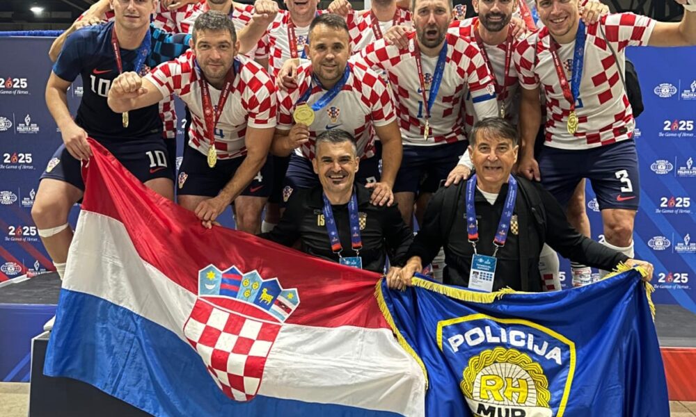 Fotografija prikazuje igrače u hrvatskim dresovima sa zlatnim medaljama oko vrata, dok su neki u plavim majicama. Ispred sebe drže dvije razvijene zastave, jednu Hrvatsku, a drugu plavu na kojoj piše 'policija'.