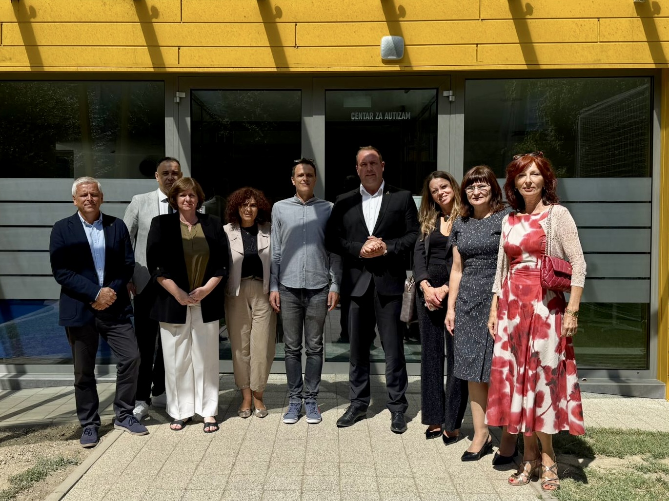 Fotografija prikazuje nekoliko ljudi ispred Centra za autizam.