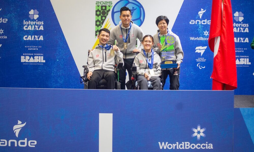 Fotografija prikazuje tri čovjeka u invalidskim kolicima s medaljama oko vrata. Oni stoje na mjestu s brojem jedan što sugerira da su osvojili prvo mjesto.