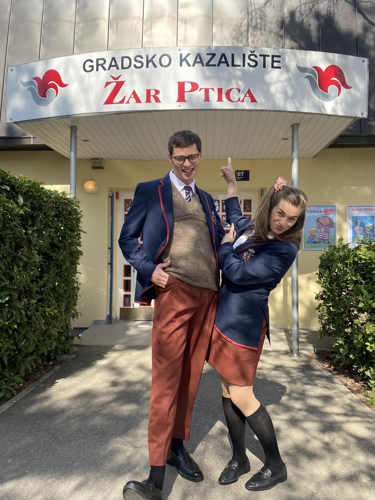 Fotografija prikazuje dvoje ljudi ispred zgrade na kojoj piše 'Gradsko kazalište Žar ptica.