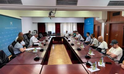 Fotografija prikazuje više ljudi koji sjede za stolom na sastanku.