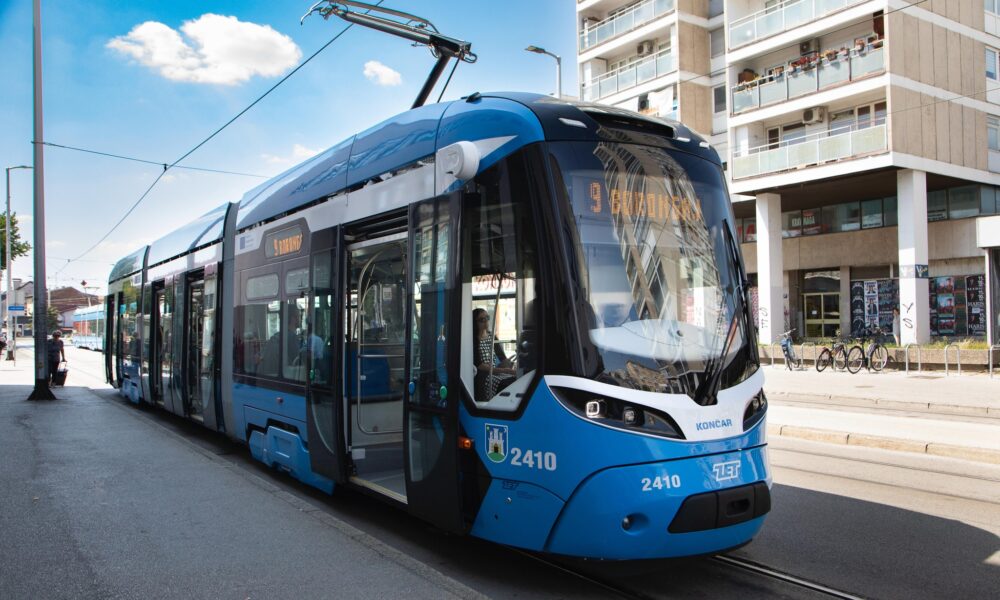 Fotografija prikazuje moderni niskopodni tramvaj na stanici, a iza njega u drugom smjeru ide staromodni tamvaj.