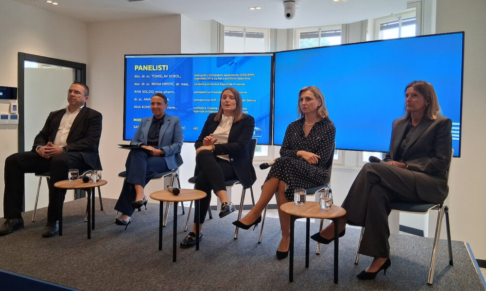 Pet panelista, tri žene i dva muškarca, sjede na pozornici ispred velikog plavog ekrana s najavom sudionika rasprave.