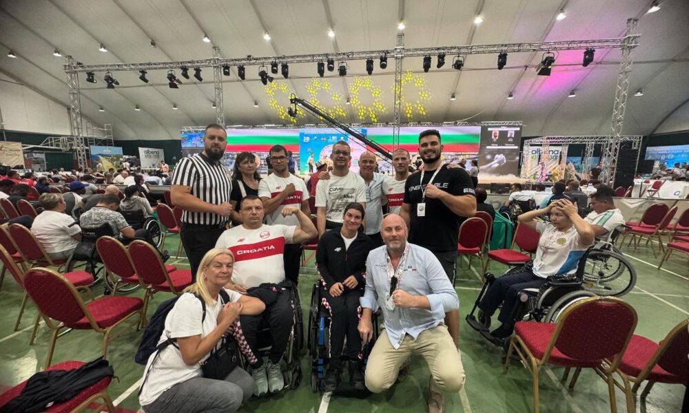 Fotografija prikazuje nekoliko ljudi kako pozira s stisnutim šakama. Neki od njih su i u invalidskim kolicima.