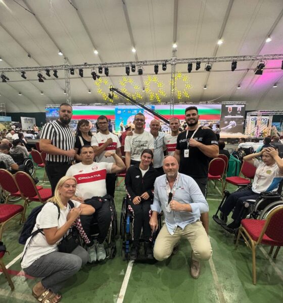 Fotografija prikazuje nekoliko ljudi kako pozira s stisnutim šakama. Neki od njih su i u invalidskim kolicima.