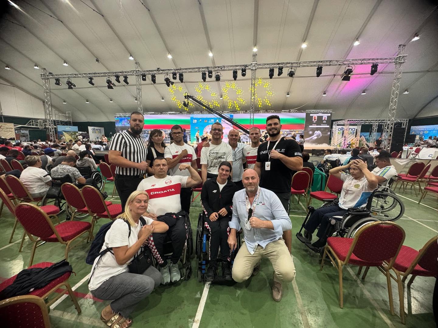 Fotografija prikazuje nekoliko ljudi kako pozira s stisnutim šakama. Neki od njih su i u invalidskim kolicima.