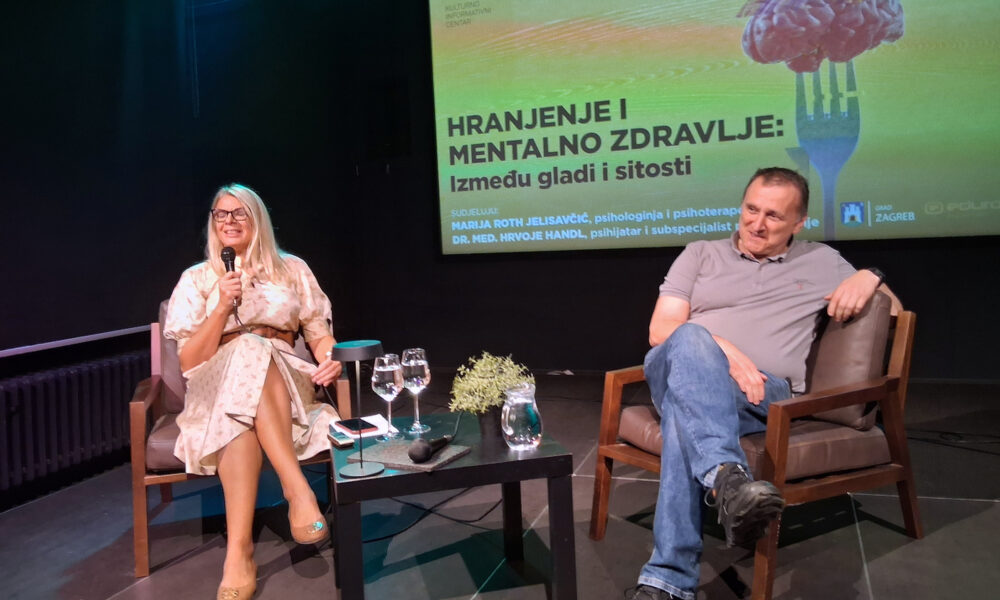 Psihologinja i psihoterapeutkinja Marija Roth Jelsaivić i psihijatar Hrvoje Handl sjede na pozornici tijekom okruglog stola o hranjenju i mentalnom zdravlju, s projekcijom naslova događanja u pozadini.