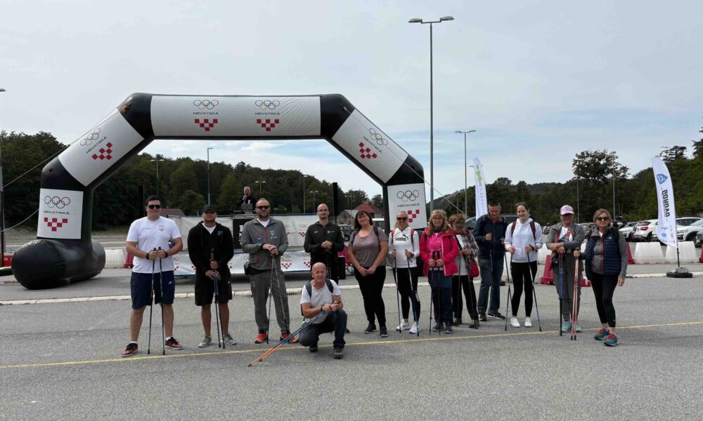 Fotografija prikazuje nekoliko ljudi neki nose štapove za nordijsko hodanje u rukama, dok je iza njih napuhana ciljni prostor na kojem je vidljivo obilježje Hrvatskog olimpijskog odbora i hrvatske šahovnice.