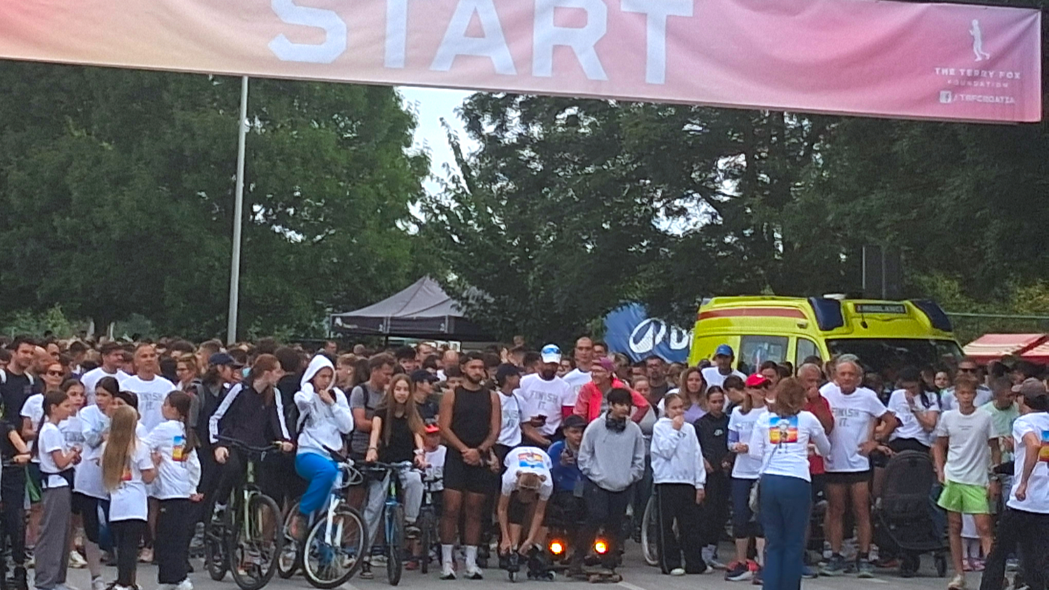 Velika skupina sudionika različite dobi stoji na startu humanitarne utrke Terry Fox Run, ispod transparenta s natpisom „START“.