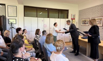 Fotografija prikazuje punu dvoranu ljudi i dvoje osoba koje se rukuju tijekom primopredaje nekog dokumenta.