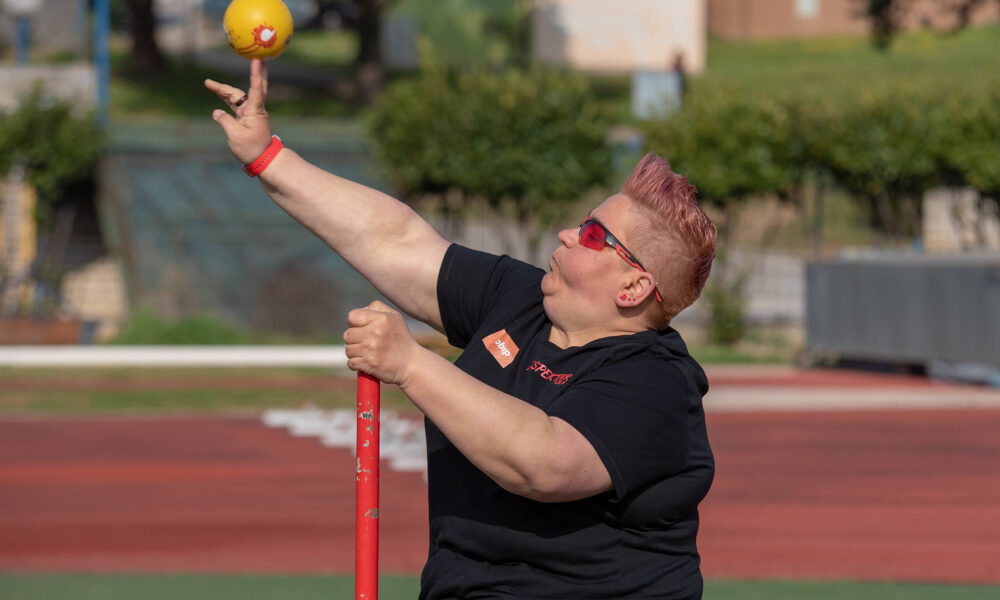 Na fotografiji je atletičarka koja baca kuglu.