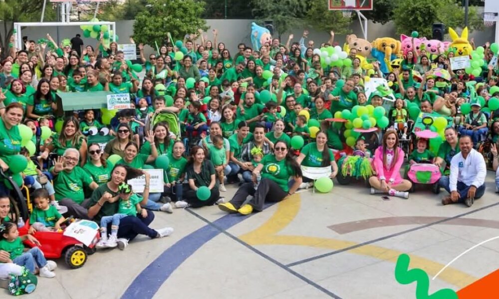 Na fotografiji se nalazi velika skupina ljudi okupljena na vanjskom košarkaškom igralištu. Svi su obučeni u zelene majice i drže zelene rekvizite poput balona i ukrasa, što stvara snažan dojam zajedništva i veselja. U pozadini se vide dva košarkaška obruča, drveće i planine, što sugerira da se događaj odvija na slikovitom mjestu, vjerojatno u prirodi. Atmosfera je svečana i razigrana — neki sudionici su maskirani u likove i maskote, što dodatno doprinosi zabavi. U gornjem desnom kutu fotografije nalazi se transparent s natpisom „#UNIQUELY CP“, koji vjerojatno označava naziv ili temu događaja. Sve zajedno izgleda kao proslava povezana sa školom, zajednicom ili posebnom prigodom.
