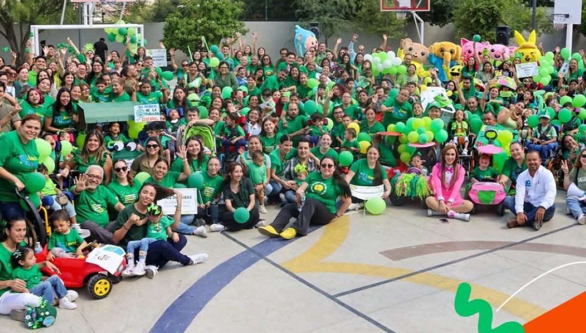 Na fotografiji se nalazi velika skupina ljudi okupljena na vanjskom košarkaškom igralištu. Svi su obučeni u zelene majice i drže zelene rekvizite poput balona i ukrasa, što stvara snažan dojam zajedništva i veselja. U pozadini se vide dva košarkaška obruča, drveće i planine, što sugerira da se događaj odvija na slikovitom mjestu, vjerojatno u prirodi. Atmosfera je svečana i razigrana — neki sudionici su maskirani u likove i maskote, što dodatno doprinosi zabavi. U gornjem desnom kutu fotografije nalazi se transparent s natpisom „#UNIQUELY CP“, koji vjerojatno označava naziv ili temu događaja. Sve zajedno izgleda kao proslava povezana sa školom, zajednicom ili posebnom prigodom.