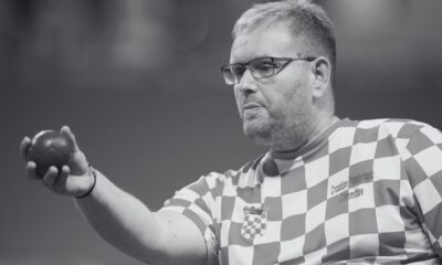 Crno-bijela fotografija hrvatskog boćara u dresu s kvadratićima, s natpisom „Croatian Paralympic Committee“. Sportaš nosi naočale i drži boću u ruci, koncentrirano gledajući prema naprijed.