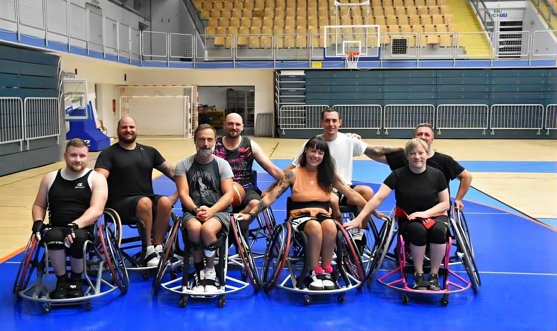 Fotografija prikazuje košarkaše u kolicima koji nose crne dresove.