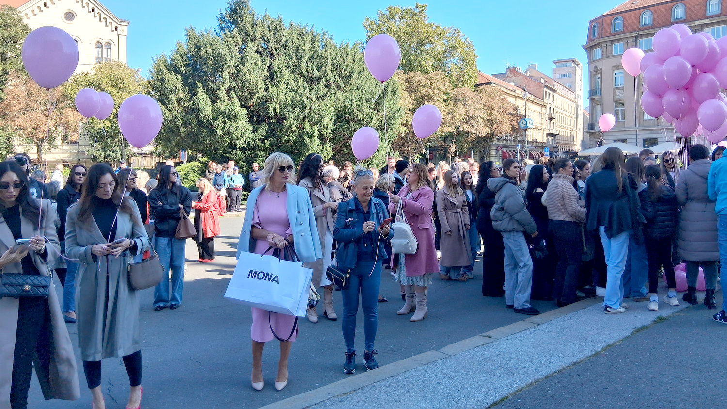Velika skupina ljudi okupljena je na otvorenom, mnogi drže ružičaste balone u znak podrške borbi protiv raka dojke tijekom Dana ružičaste vrpce.
