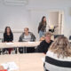 Sudionice edukacije sjede za stolovima s radnim materijalima tijekom predstavljanja aplikacije Danova Next u prostorijama s EU obilježjima.