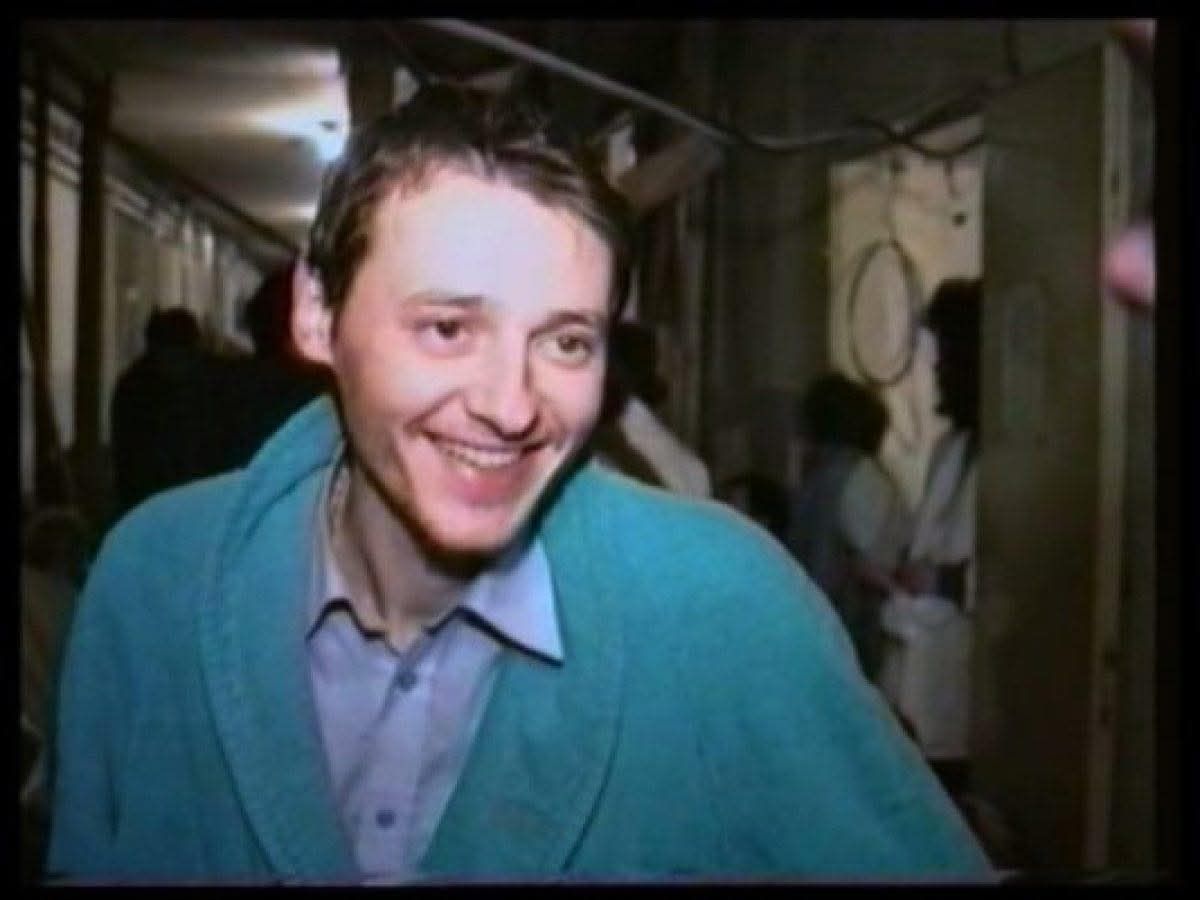 Na fotografiji je čovjek u zelenom džemperu i košulji koji se smije.