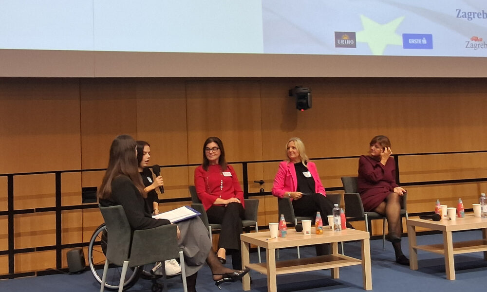 Pet žena sudjeluje u panel-raspravi o inkluzivnom obrazovanju; jedna od njih u invalidskim kolicima govori na mikrofonu, dok ostale sjede i slušaju.