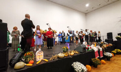 Sudionici i organizatori stoje na pozornici ukrašenoj jesenskim plodovima i cvijećem tijekom svečanog proglašenja izbora za Najbolju baku i djeda 2025. godine.