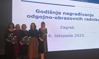 Pet žena stoji na pozornici s priznanjima u rukama ispred velikog ekrana s natpisom „Godišnje nagrađivanje odgojno-obrazovnih radnika, Zagreb, 6. listopada 2025.“