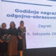 Pet žena stoji na pozornici s priznanjima u rukama ispred velikog ekrana s natpisom „Godišnje nagrađivanje odgojno-obrazovnih radnika, Zagreb, 6. listopada 2025.“