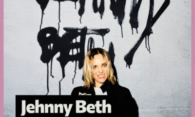 Promotivna slika glazbenice Jehnny Beth. Na slici stoji ispred zida na kojem je crnim, kapajućim sprejem ispisano njezino ime. Gleda prema kameri s intenzivnim izrazom lica, djelomično razbarušene svijetle kose. Pri dnu slike nalazi se crni pravokutnik s velikim bijelim natpisom “Jehnny Beth”. Slika je uokvirena ružičastim obrubom.
