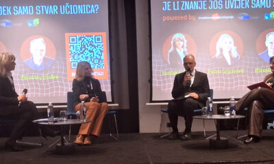 Četvero sudionika sjedi na pozornici tijekom panel-rasprave, ispred projekcije s naslovom „Je li znanje još uvijek samo stvar učionica?“ i prikazanim imenima govornika.