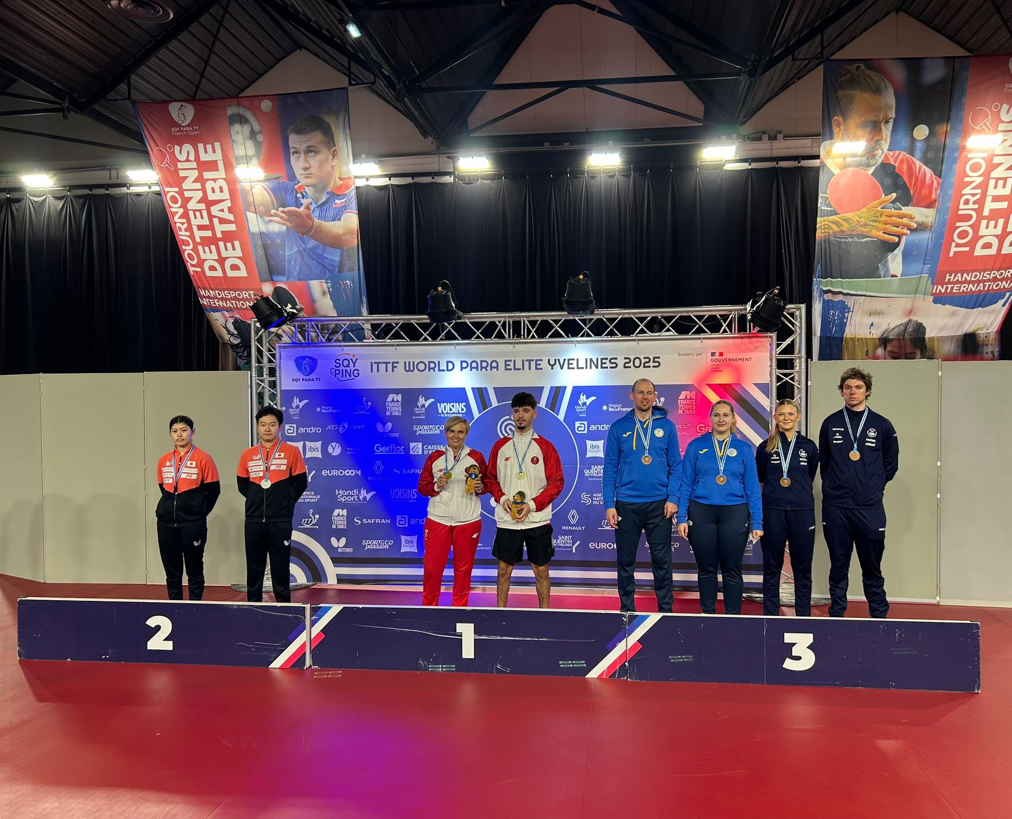 Fotografija prikazuje nekoliko ljudi kako stoji na postolju s medaljama oko vrata.