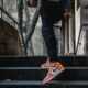 Fotografija prikazuje osobu u narančastim nike tenisicama kako se panje niz stepenice.
