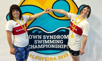 Fotografija prikazuje dvije osobe s Down sindromom kako se drže za ruke. Iza njih stoji logo natjecanja na kojem piše '8 European open'.