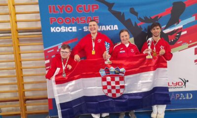 Fotografija prikazuje troje sportaša sa medaljama oko vrata i jednim peharom. Oni ispred sebe drže razvijenu hrvatsku zastavu.