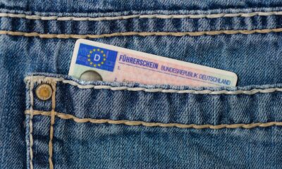 Njemačka vozačka dozvola djelomično je umetnuta u prednji džep traperica, vidljiv je njezin gornji dio s oznakom “Führerschein Bundesrepublik Deutschland”.