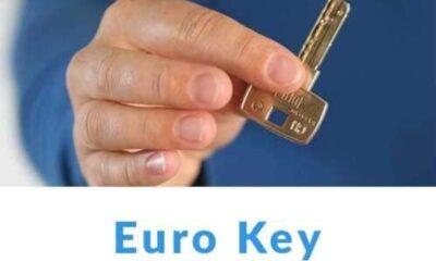 Fotografija prikazuje krupni plan ruke koja drži metalni ključ s oznakom "Euro Key". Ključ ima pravokutnu glavu i nazubljenu oštricu, što sugerira da je dizajniran za specifičan tip brave – vjerojatno prema europskim standardima. Pozadina je zamućena, čime se pažnja usmjerava isključivo na ključ i ruku koja ga drži. Ispod fotografije nalazi se natpis "Euro Key" u plavoj boji, jasno istaknut. Ova fotografija vjerojatno služi za edukaciju ili promociju vezanu uz sigurnosne sustave, brave ili pristupne tehnologije.
