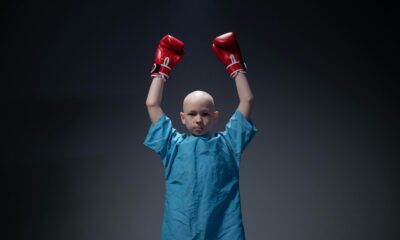 Na fotografiji je dijete koje nosi plavu bolničku haljinu i crvene boksačke rukavice, s obje ruke podignute visoko iznad glave u pobjedničkoj gesti. Pozadina je tamna i jednostavna, što dodatno ističe dijete u središtu slike. Dijete je ćelavo, što može upućivati na medicinsko liječenje poput kemoterapije. Cjelokupna kompozicija fotografije snažno simbolizira hrabrost, borbenost i pobjedu nad izazovima — dijete kao mali borac koji se ne predaje.