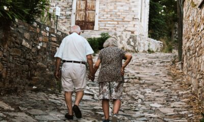 Fotografija prikazuje dvoje straih ljudi kako jedno drugog drže za ruku i hodaju.