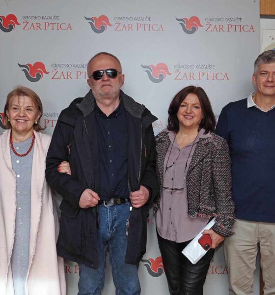 Šest osoba stoji u nizu ispred pozadine s logom „Gradsko kazalište Žar ptica“. Svi poziraju i osmjehuju se prema kameri. U pozadini se vidi i ilustracija velike plave ptice. Osobe su obučene u jesensku ili zimsku odjeću, a atmosfera je formalna, ali prijateljska, kao na službenom događanju ili susretu.