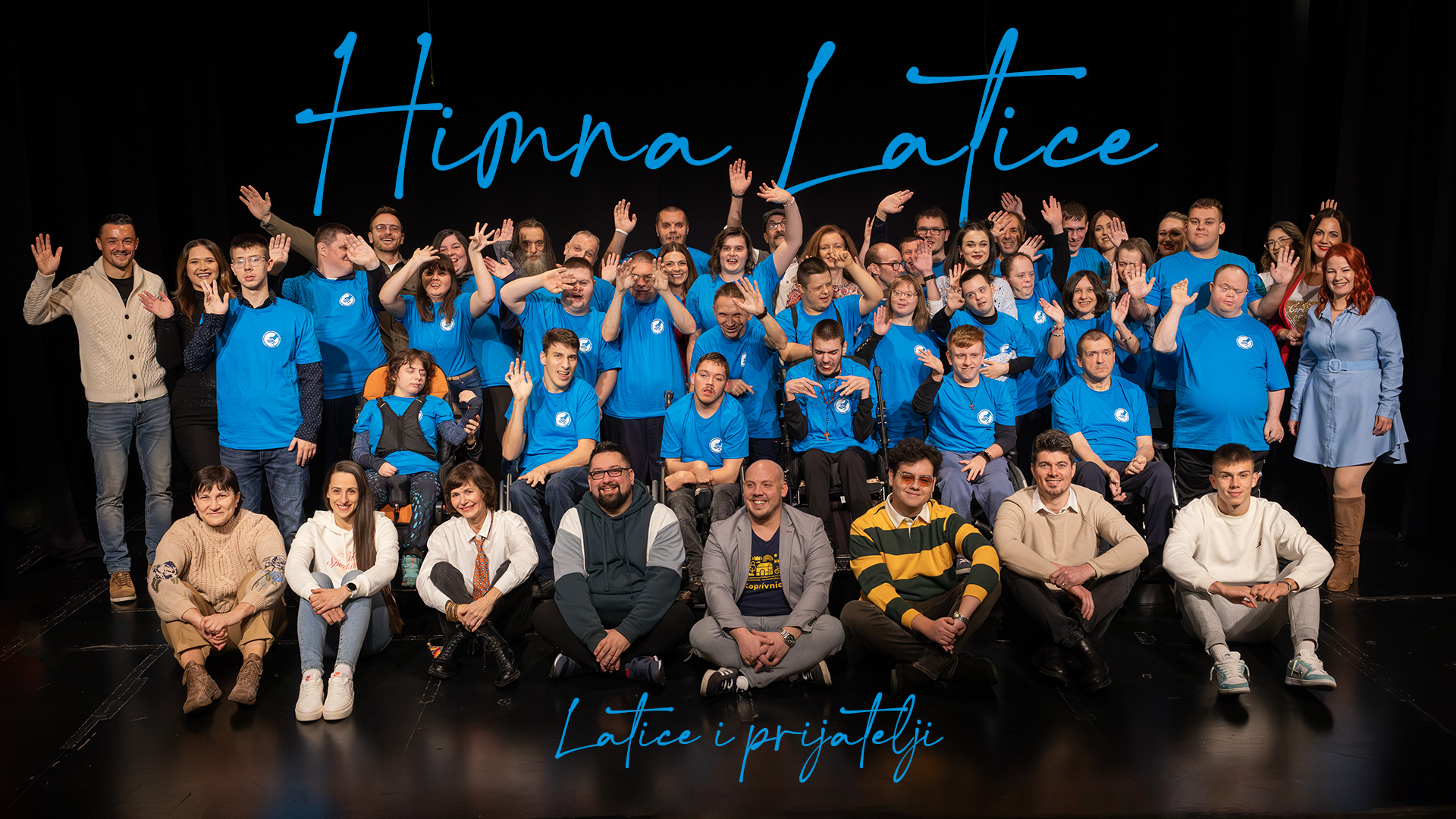 Na pozornici se nalazi velika skupina ljudi, raspoređena u nekoliko redova. Većina osoba u sredini i stražnjem dijelu nosi plave majice s bijelim kružnim logotipom, što upućuje na pripadnost istoj organizaciji ili sudjelovanje u zajedničkom događaju. U prednjem redu sjede ili kleče osobe u ležernoj odjeći, vjerojatno gosti, podržavatelji ili prijatelji. Svi izgledaju vedro i srdačno – mnogi mašu prema kameri, a osmijesi dominiraju licima. Pozadina je crna, što dodatno ističe plave majice i tekst ispisan svijetloplavim rukopisnim fontom: „Himna Latice“ i „Latice i prijatelji“.