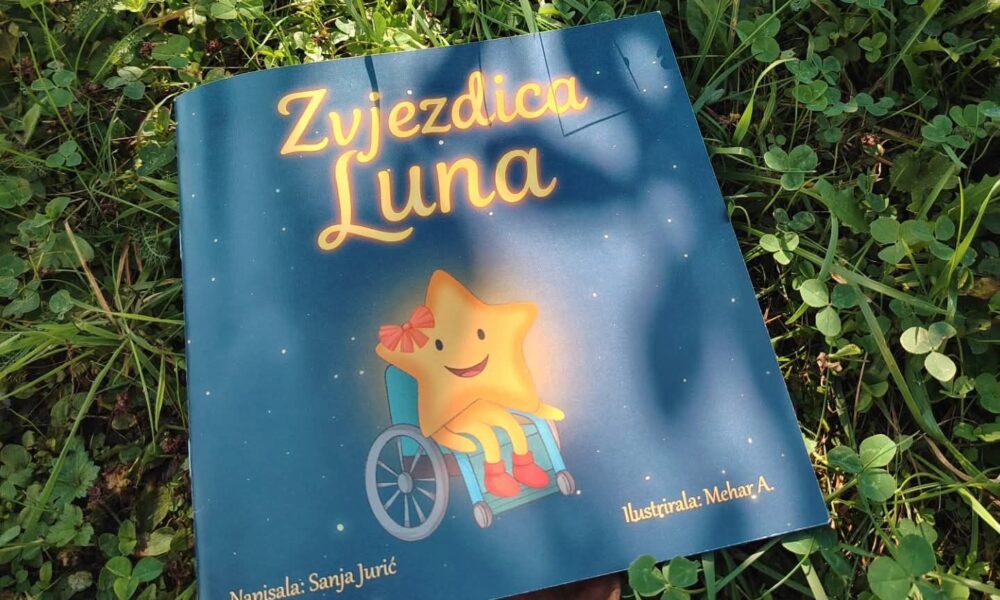 Fotografija prikazuje dječju knjigu pod nazivom „Zvjezdica Luna”, položenu na zelenoj travi među listovima djeteline. Na naslovnici je ilustracija nasmiješene zvjezdice s crvenom mašnom, koja sjedi u invalidskim kolicima. Pozadina je tamnoplava, posuta malim zvjezdicama, stvarajući dojam noćnog neba. Ispod ilustracije stoji tekst: „Napisala: Sanja Jurić” i „Ilustrirala: Mehar A.”, što označava autoricu i ilustratoricu knjige. Ova fotografija ističe inkluzivnost u dječjoj književnosti, prikazujući lik s invaliditetom na pozitivan, vedar i empatičan način. Vizualna kompozicija odiše toplinom, pristupačnošću i nježnošću, idealna za edukativne i emocionalno osjetljive kontekste.