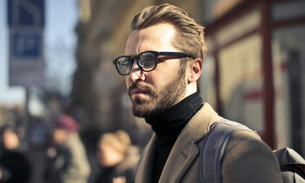 Fotografija prikazuje čovjeka s naočalama u koji se načazi u vanjskom okruženju.