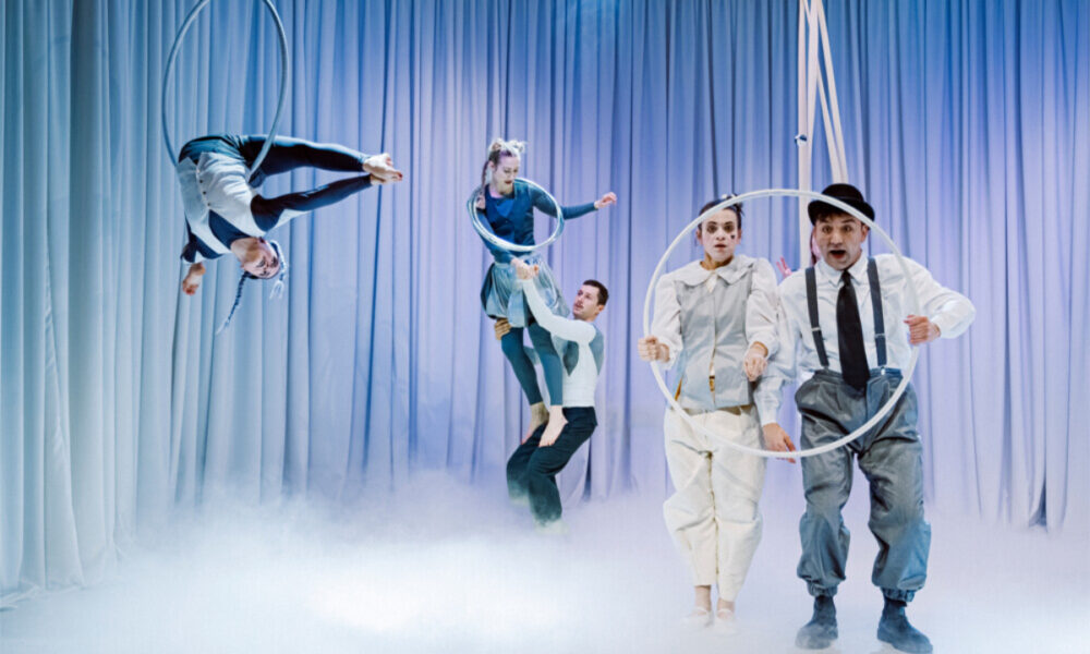 Izvođači na sceni izvode akrobacije s obručima u predstavi „Bijeli klaun“.