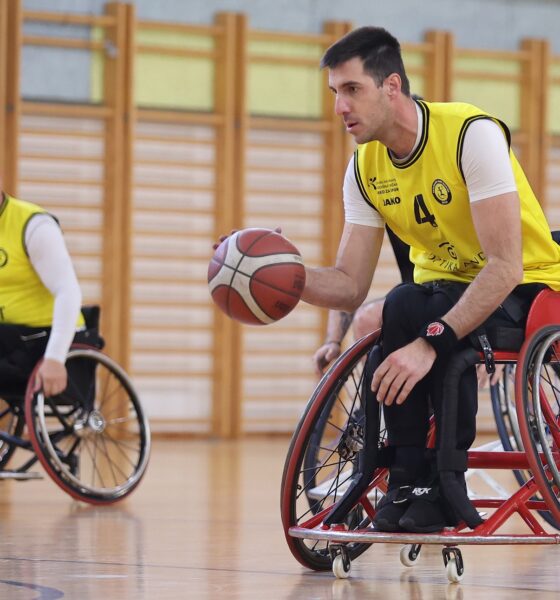 Fotografija prikazuje košarkaša u kolicima u žutom dresu kako vodi loptu.